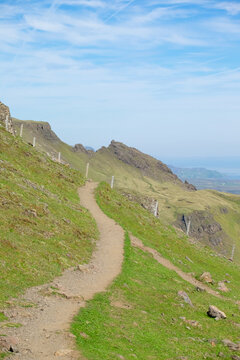 Hiking trail in Scottish terrain with green field and cliff. Adventurous trail for outdoor activity on the hill. A dirt path leading to nowhere. A serene place for peace of mind. 