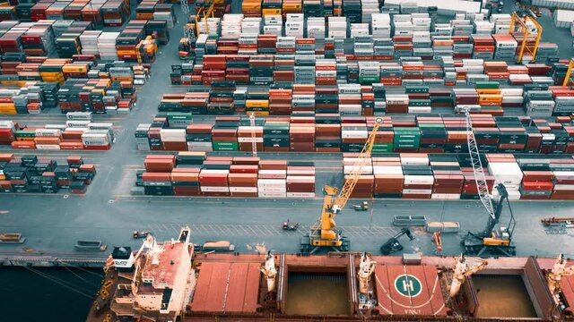 Busy container port loading and unloading cargo ship, aerial hyperlapse