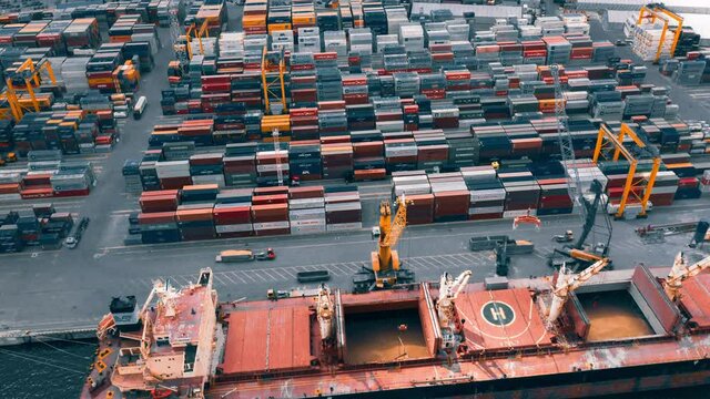 Busy container port loading and unloading cargo ship, aerial hyperlapse