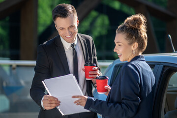 Cheerful business man and woman with coffee and papers.