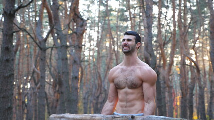 Muscular man lifting hard weight training biceps. Strong and hardy guy working out outdoor at sunset background. Athlete with naked torso exercising in nature. Concept of sport lifestyle. Dolly shot