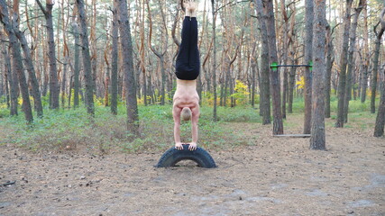 Muscular man training in forest doing handstand. Strong gymnast working out at nature environment....