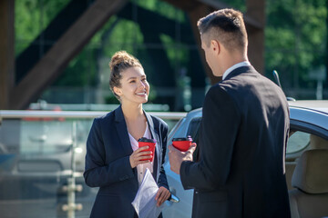 Successful woman with coffee and papers and man standing
