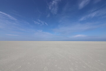 Fototapeta na wymiar A beautiful blue sky over a wide white beach.