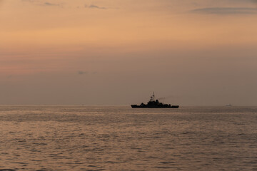 Obraz premium Silhouette of a warship sails along the trade route to protect national resources from illegal activities at sea when the evening before sunset.