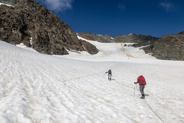 Climbers team on a trail through a dangerous glacier and avalanches in Austiran Alps. Route to the Grossglockner rock summit, Austria