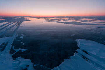 Early morning on the ice of lake Baikal against the background of mountains and ice
