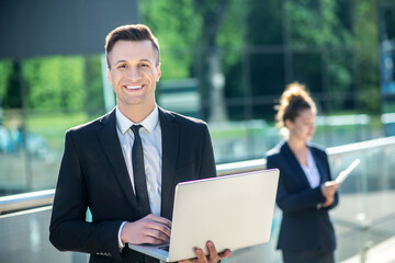 Happy smiling young man with laptop outdoors.