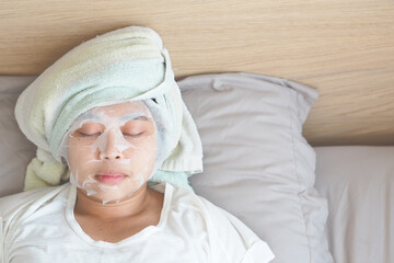 Soft focus on Asian young woman with a sheet mask on her face. - Wellness face care and Spa Concept.