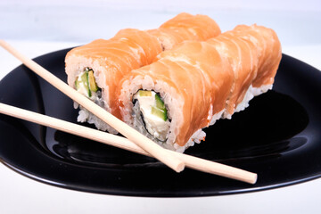 Philadelphia sushi rolls set on black plate with chopsticks