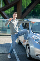Young adult man standing near a car showing keys