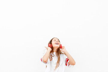 Girl listening to music with wireless headphones with white background. Girl enjoying music with close eyes and laughing. Lifestyle concept. Happy concept.