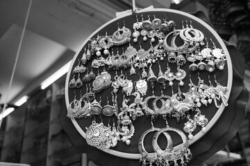 Handmade earrings hanging for sale for tourists at the street market in Udaipur India. Colorful handmade beautiful and stylish earrings for sale at outside street market. Black and White Image.