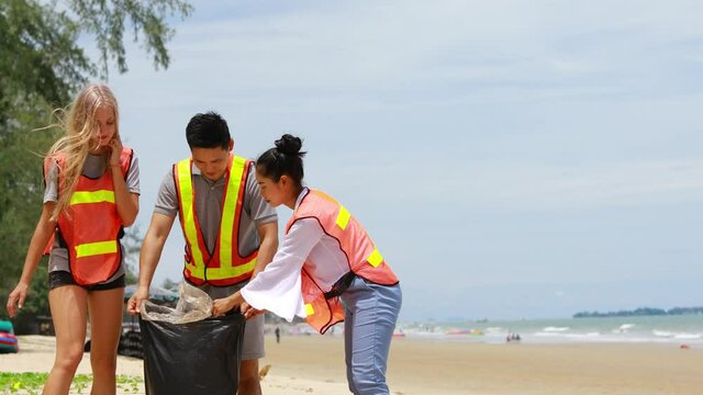 A group of volunteers pick up trash into garbage bag in public beach. CSR activity, Environmental problem
