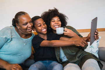 Grandmother, mother and son taking a selfie with digital tablet.