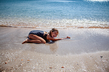 Fototapeta na wymiar happy girl child playing in the shore of the sandy beach.
