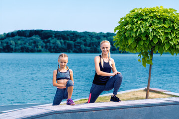 Portrait of mother and child in sport style clothes on the shore of the lake.