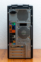 Die Rückseite eines High-Tower-PC auf einem Holztisch vor einer weißen Wand