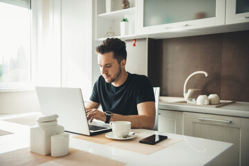 Caucasian man with beard resting at the computer in kitchen
