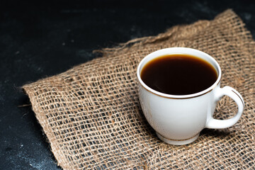 A cup of coffee on a linen napkin. Coffee beans on the table.