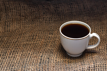 Obraz na płótnie Canvas A cup of coffee on a linen napkin. Coffee beans on the table.
