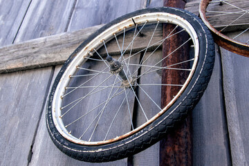 An old bicycle wheel hangs on a wooden fence.