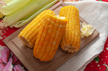 cooked corn with butter on wooden board and colorful table