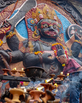 Hindu state of Lakshmi on the side of a temple with oil lamps burning