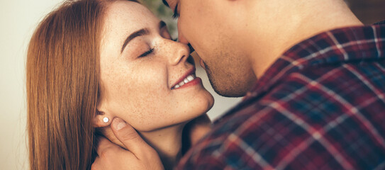 Caucasian couple smiling and kissing in the living room while girl has freckles and red hair