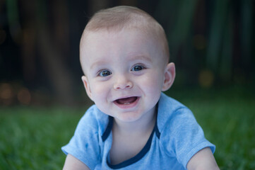 Portrait of a one year old boy smiling straight at camera, isolated against a blurry background.