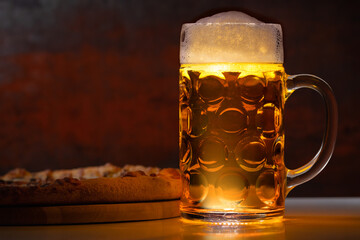 Frothy pint of beer in a tankard with pizza