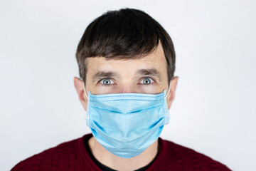 A man with big frightened eyes with a medical mask on his face, his whole face is covered with a mask. The man is frightened by the bad environment and dangerous viruses everywhere