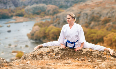 Athletic young woman doing the splits on a rock