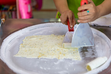 process of making fried ice-cream. Thailand stir-fried ice cream rolls at freeze pan. Organic, natural rolled ice cream, hand made dessert. Fried ice cream machine with steel chilled pan.