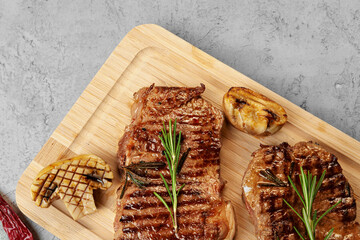 Two grilled beef steaks on wooden board