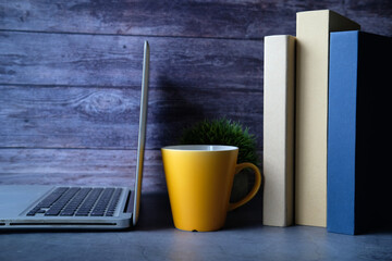 stack of books and laptop on table 