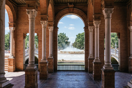 View of the fountain in Plaza de Espa&ntilde;a between the arches on a sunny day, Seville, Andalucia Horizontal photograph