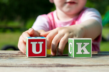 Children's hands hold learning cubes with English letters. Summer alphabet courses.