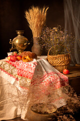 Samovar on the table with tea, bread, apples. Clay jug with yellow ears of wheat.