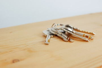 Bunch of keys on a shaped keychain at wooden table background. Concept for real estate or renting home with copy space,Close up.
