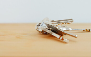Bunch of keys on a shaped keychain at wooden table background. Concept for real estate or renting...