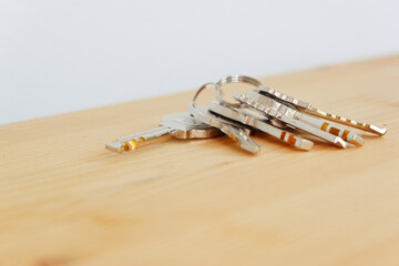Bunch of keys on a shaped keychain at wooden table background. Concept for real estate or renting home with copy space,Close up.
