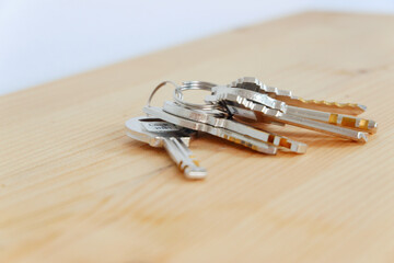 Bunch of keys on a shaped keychain at wooden table background. Concept for real estate or renting home with copy space,Close up.
