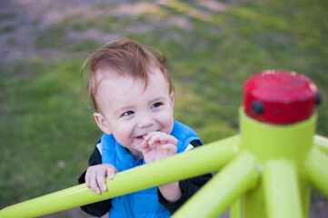 Fototapeta na wymiar A baby smiles in a park's playgroung.