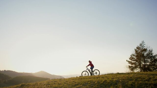 Active senior woman with e-bike cycling outdoors in nature.