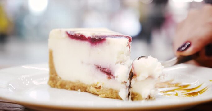 Close up of cheese cake new york on white plate. Woman cut in with fork and take. Delicious favorite pastry