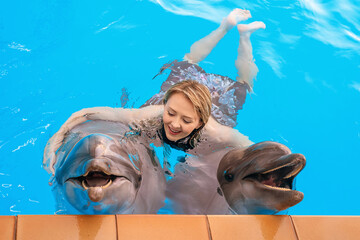 The dolphin therapy session. Young girl smiles and hugs two dolphins © Oleksandr