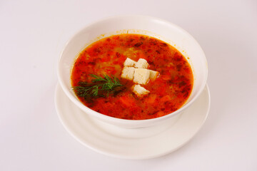 Red soup served with croutons and dill. Soup with tomatoes. White background