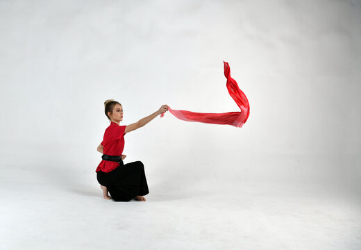 beautiful girl in black and red is doing exercises with a red scarf