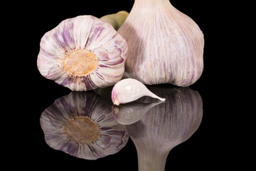 Fresh heads of garlic and clove of garlic on black background, mirror reflection